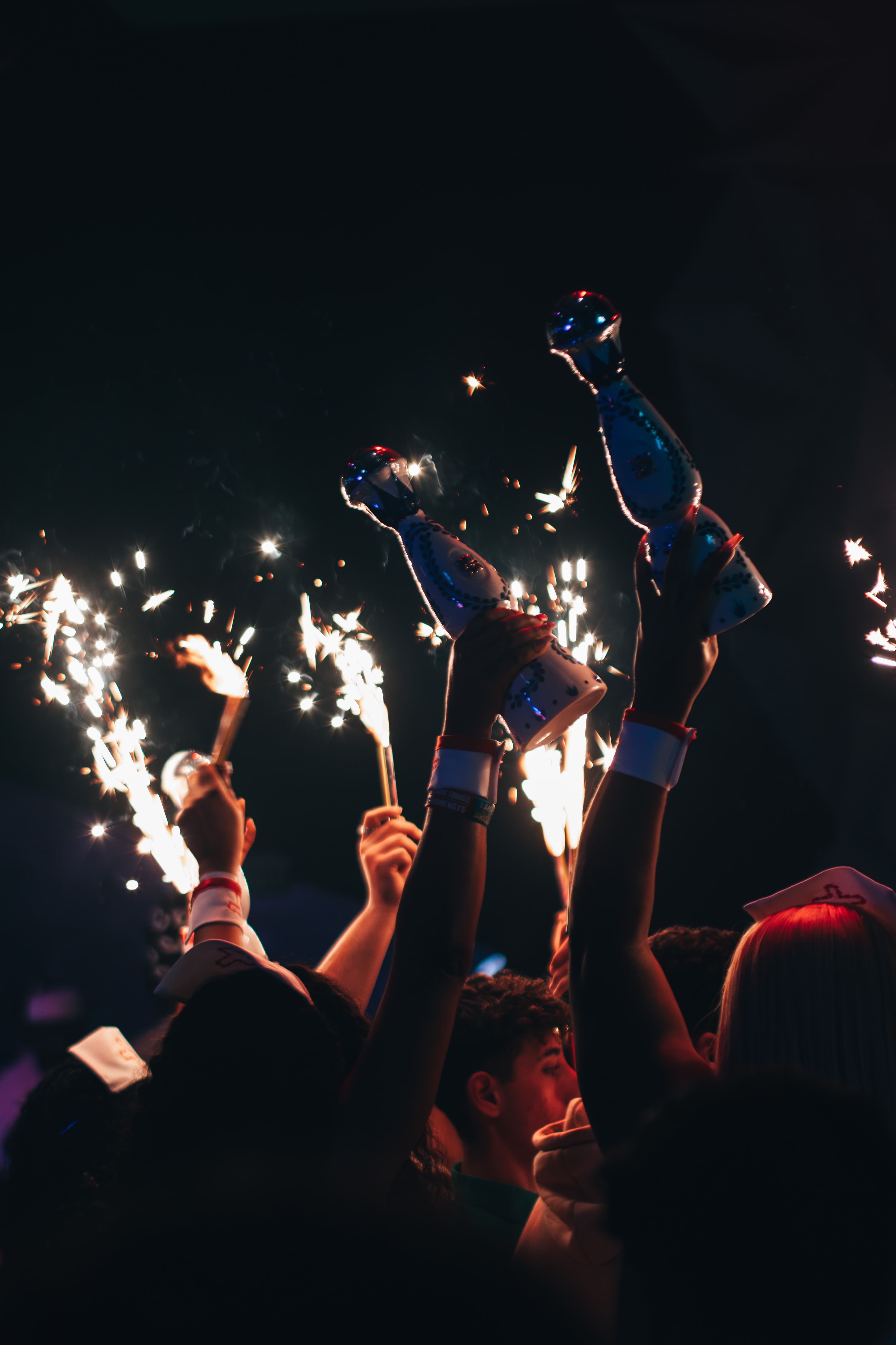 Guests raising sparkler-topped bottles above the crowd at a nightclub